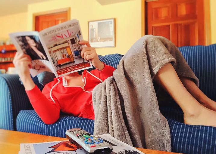 Žena relaxuje na gauči, číta časopis